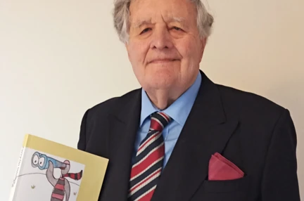 Chris holding up a copy of his book called Carry on Smiling