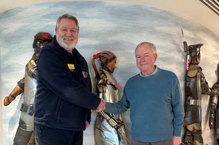 Member Jim visiting Rustington to make his donation shaking hands with a staff member in front of their statue