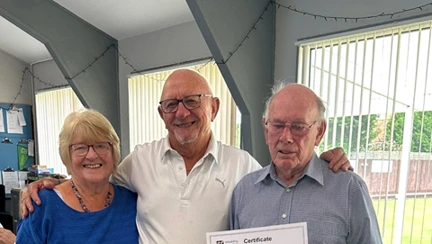 Veteran holding a certificate and standing with two other bowlers