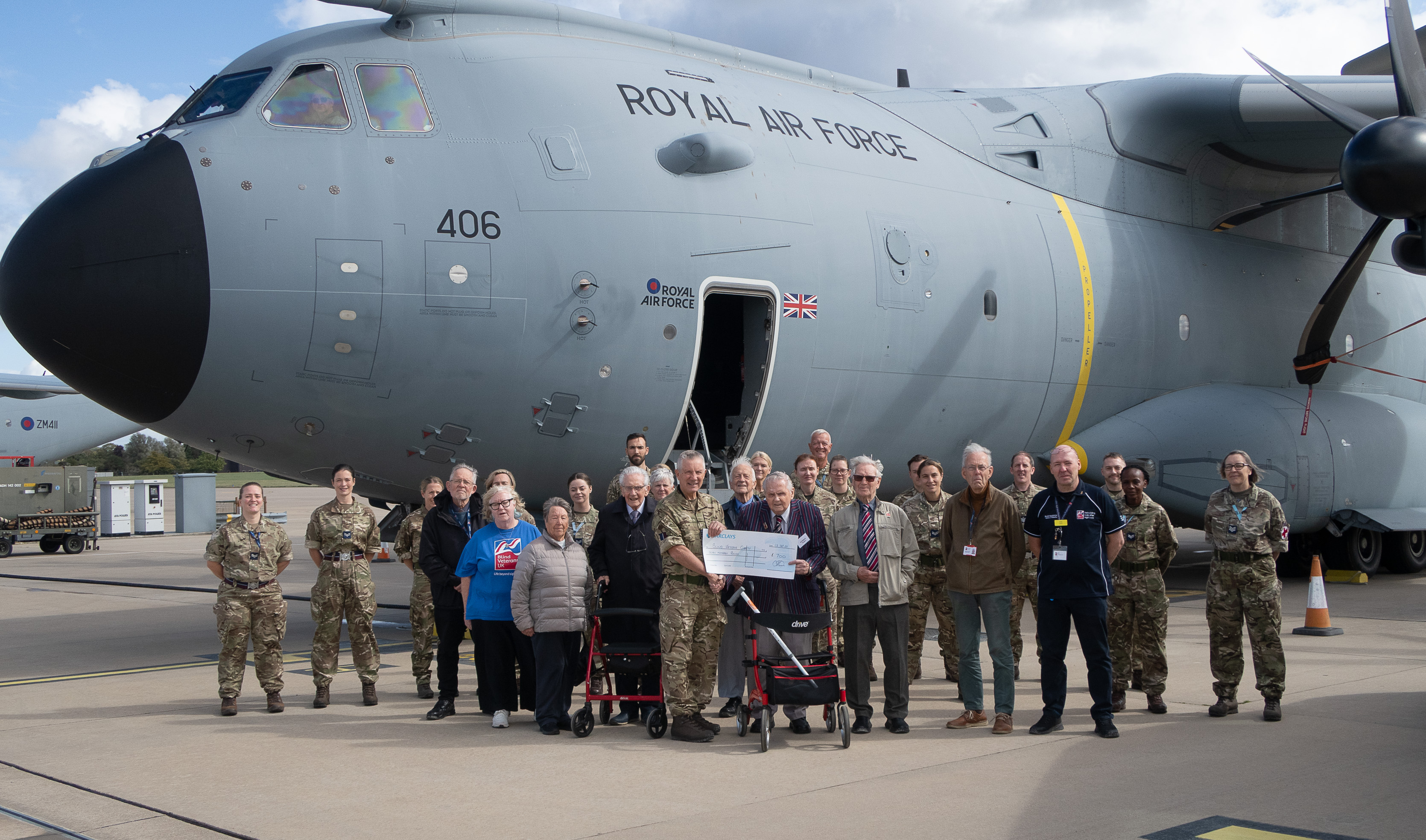 A large group photo of everyone involved in the Brize Norton visit including our veterans and staff and personnel from the military base. The group are stood in front of an A400M military transport aircraft