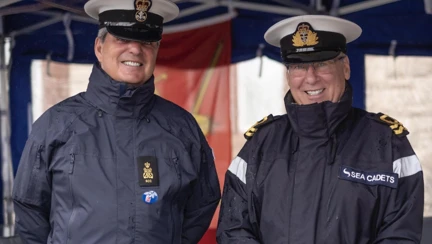 Two men wearing sailor caps and waterproof jackets with a label which reads: "Sea cadets"