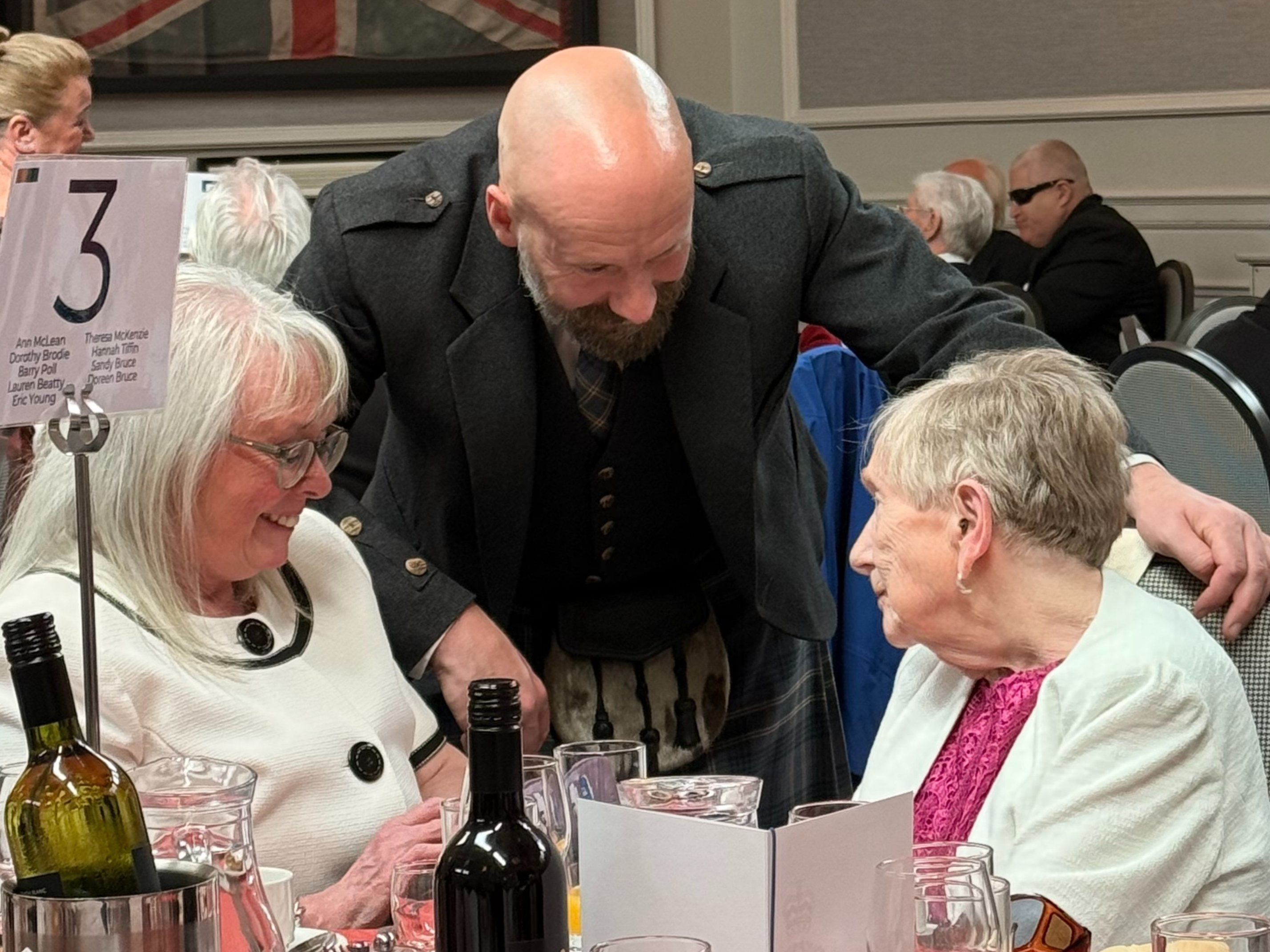 Staff member Scott leaning into congratulate blind veteran Ann