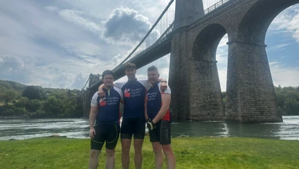 James stood with his arms around Tom and Aled in front of Menai Bridge