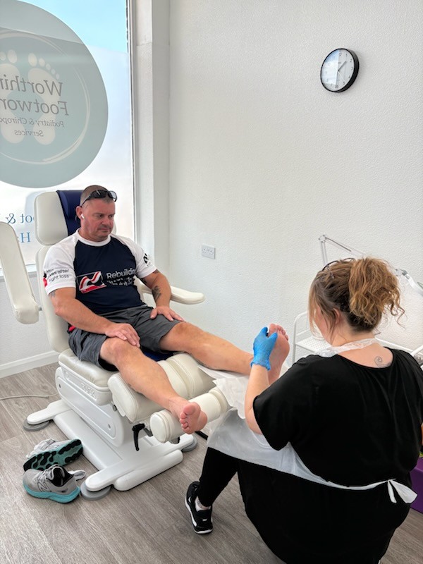 Stu sat in a chair while Kate works on his feet