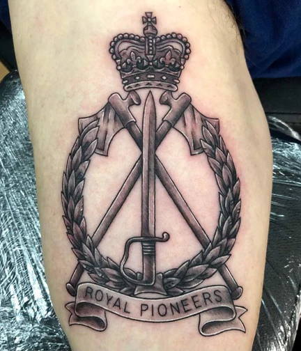 A close up photo of a tattoo of the Royal Pioneers cap badge on an arm