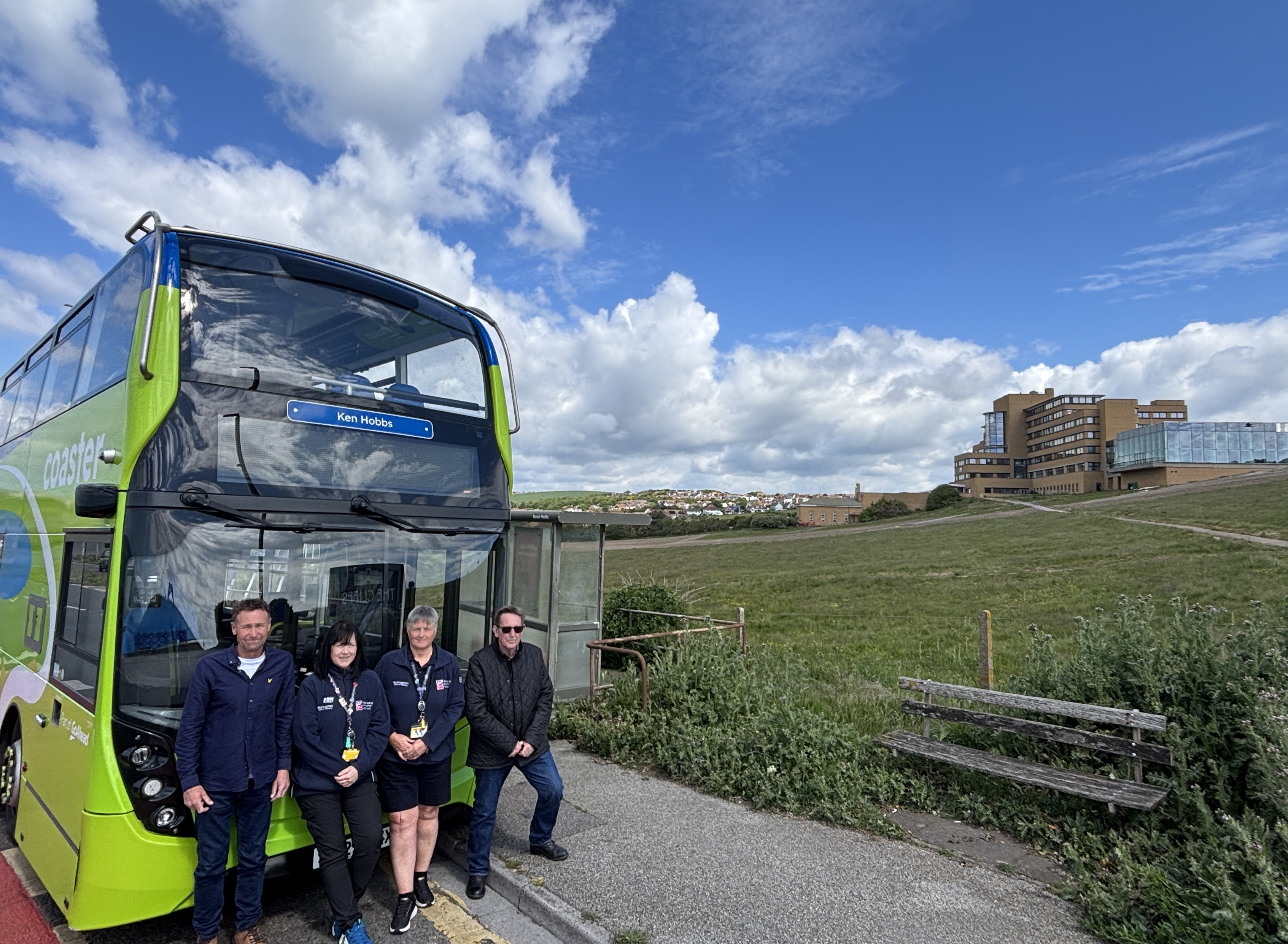 A Brighton & Hove Buses Coaster bus parked near the former Blind Veterans UK rehabilitation centre in Ovingdean, with people standing beside it.