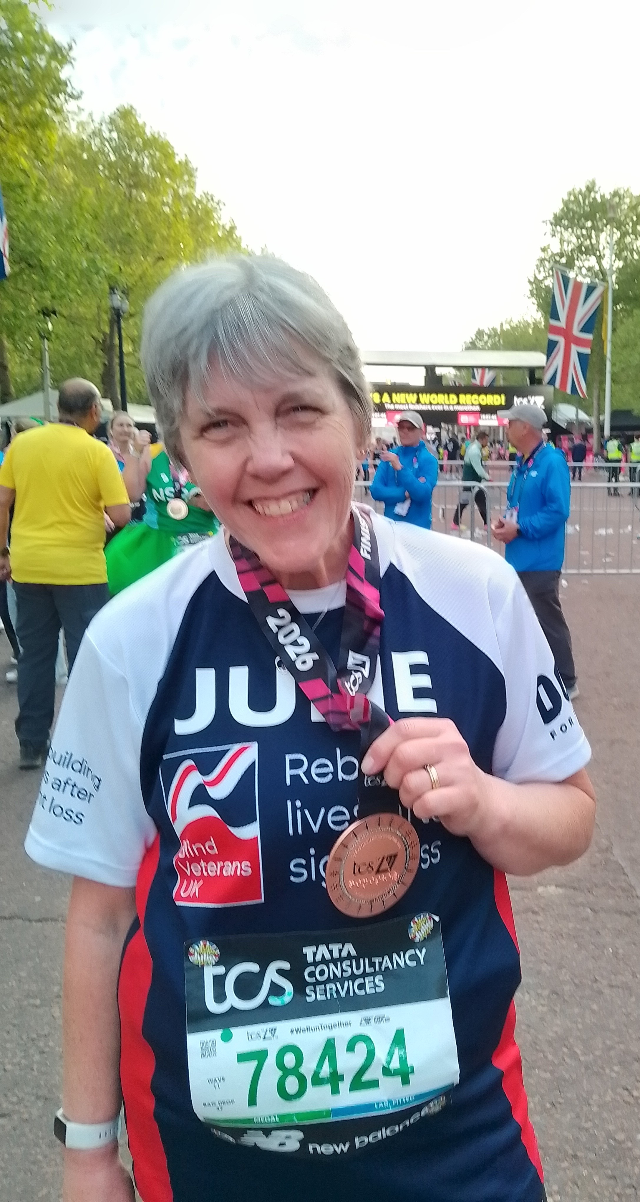 Julie smiling brightly with her London Marathon medal around her neck