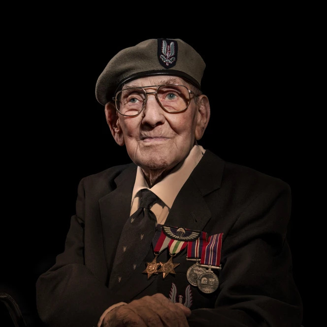 Matt photographed against a black background, wearing his badges and cap