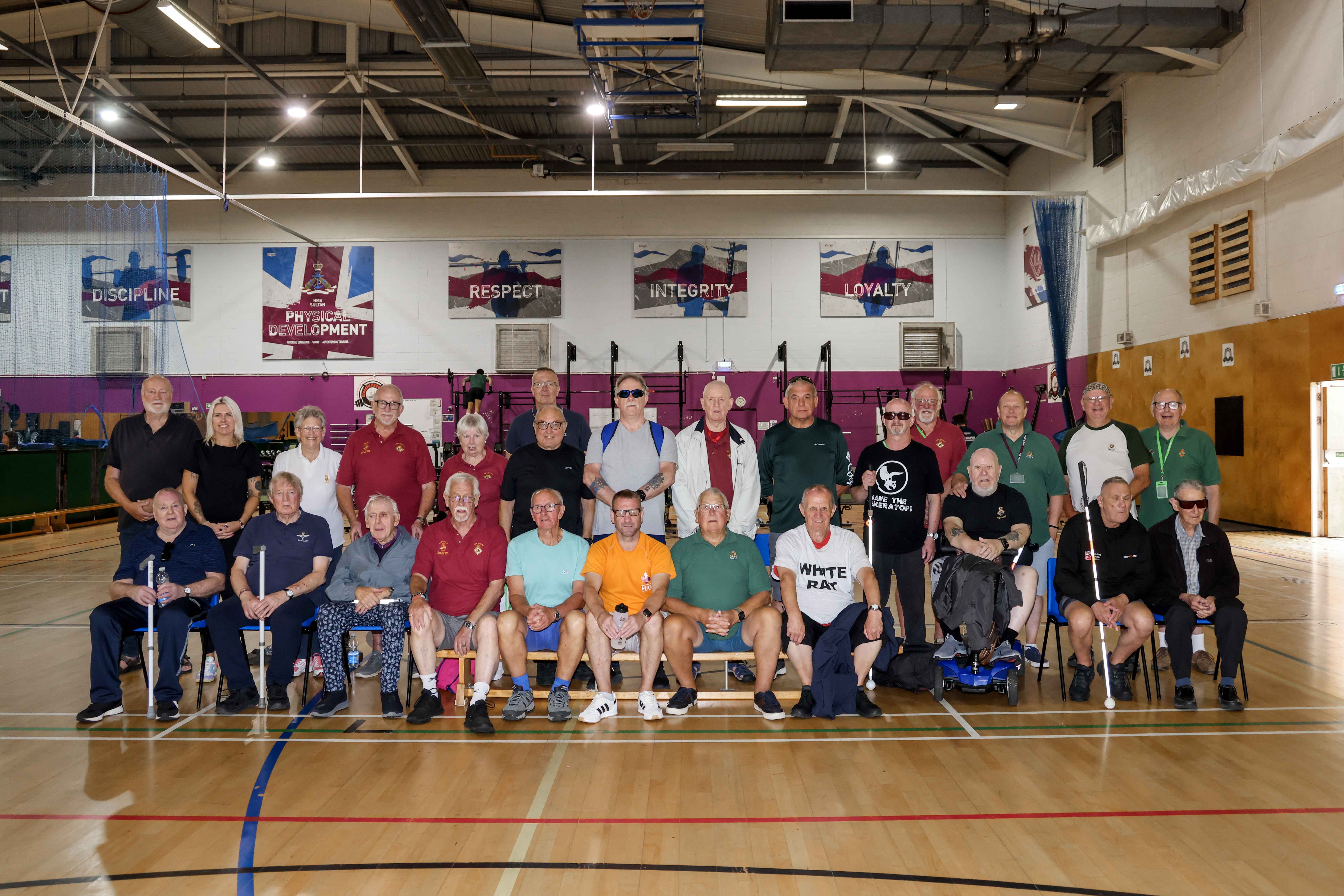 26 people group together for a team photo in a gymnasium