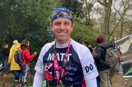 Matt smiling with his medal around his neck and wearing his Blind Veterans UK running top
