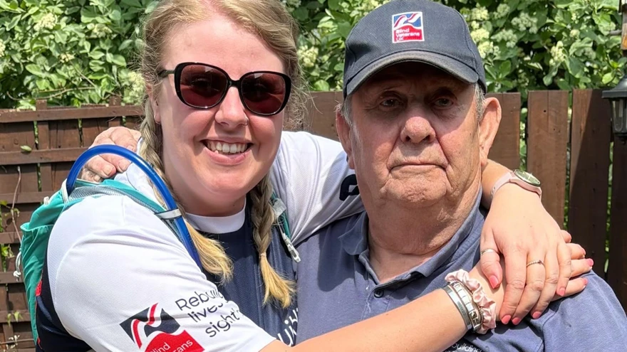 Rebecca wearing her Blind Veterans UK top with her arms around the neck of her Granda Brian.