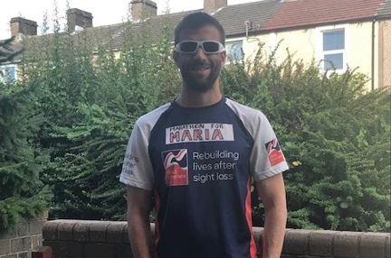 Darren stood in his garden wearing his Blind Veteran UK running top