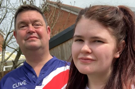 Megan and Clive standing together. Megan is wearing her Blind Veterans UK running top and Clive is in his Great Britain archery shirt