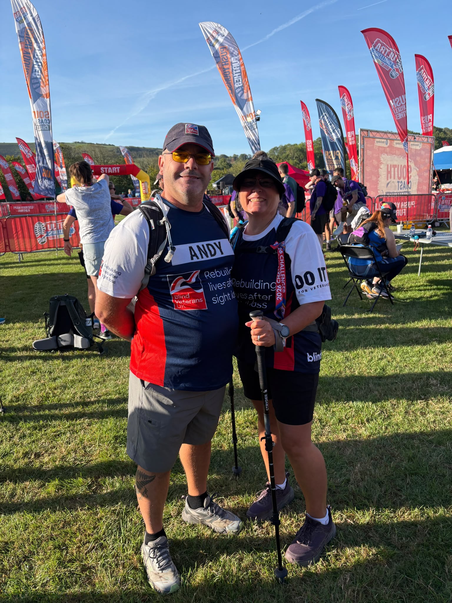 Andy and Angie standing together at the start of the challenge surrounded by colourful flags