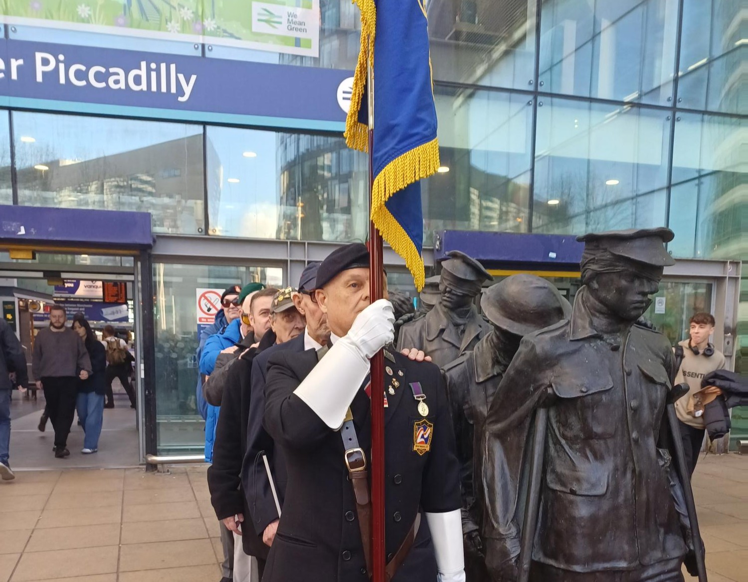 blind veteran stand bearer alongside victory over blindness statue at Manchester Piccadilly station