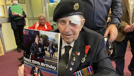 Blind veteran Ken smiling and holding up the card of himself and Margaret