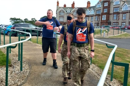 Heading out with the Llandudno Centre in the background. One person is guiding his blindfolded colleague.