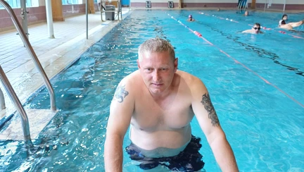 Lee in the pool leaning against the side for a photo