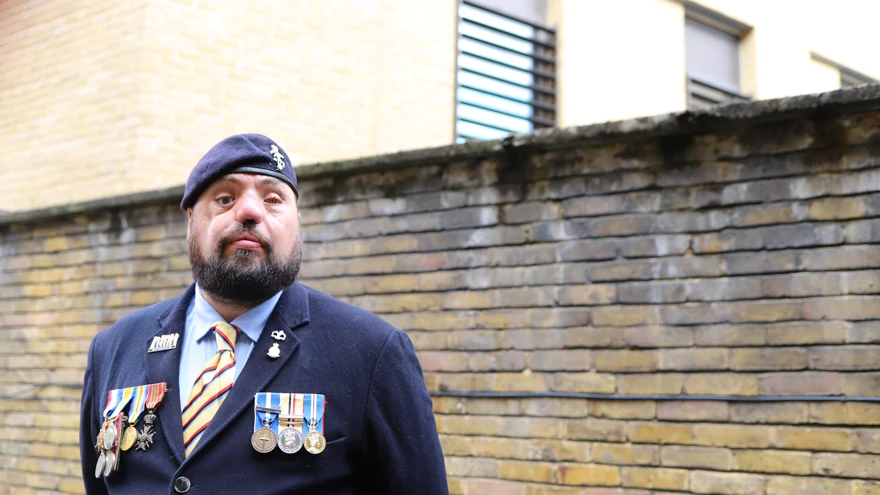 Blind veteran Simon wearing a navy suit, with his military medals and beret