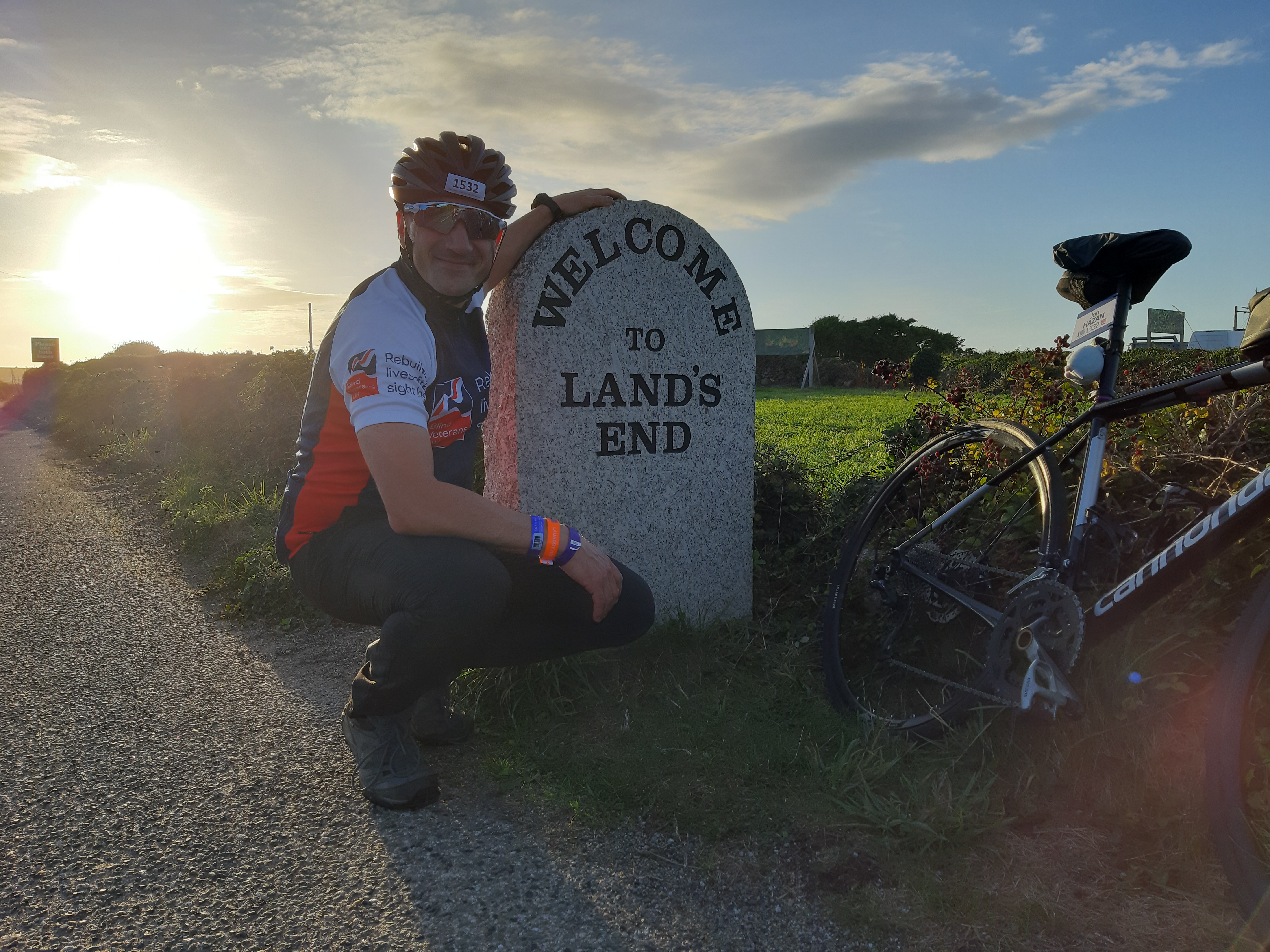 Jon crouched down next to a stone sign for Lands End