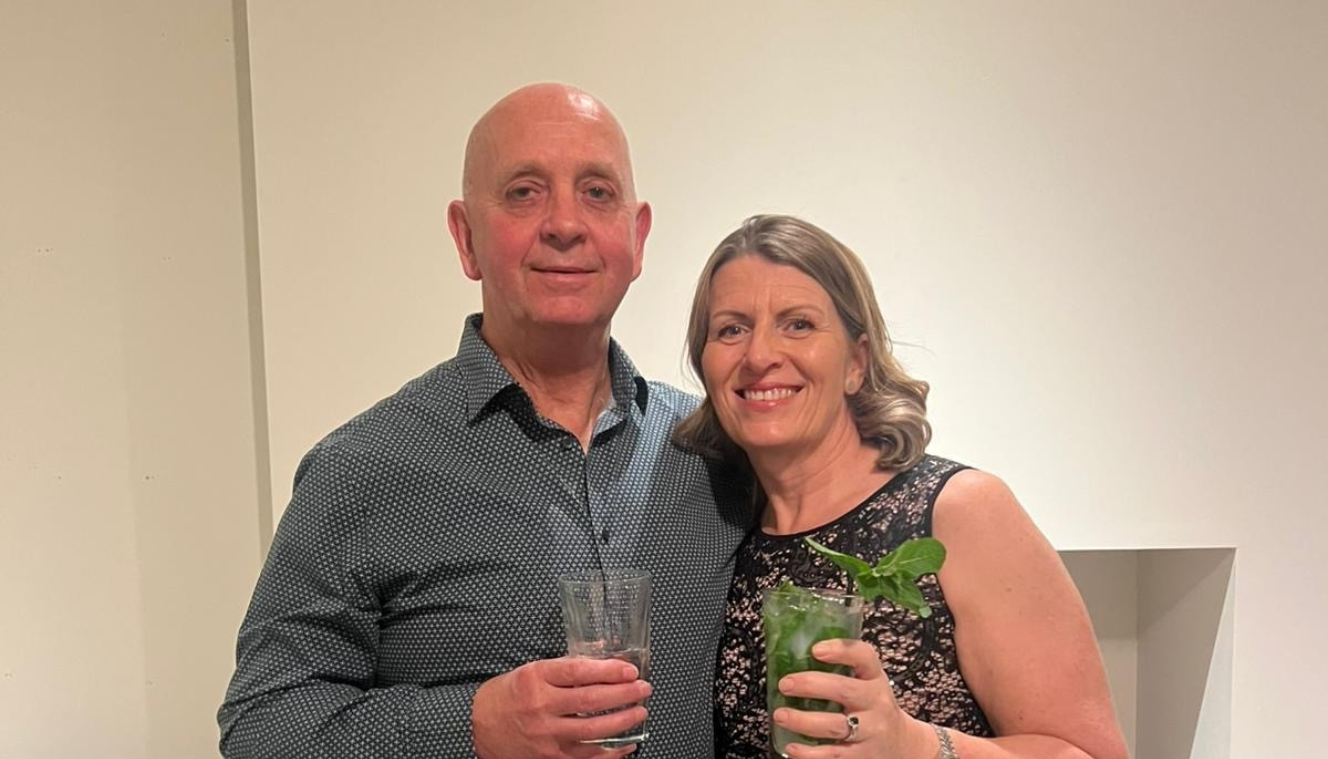 Image shoes the blind veteran Andy and his wife, Julie standing next to each other, each raising a drink