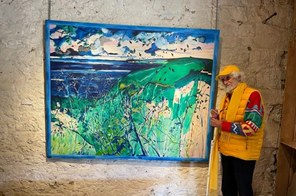 Blind veteran Philip stands with a white cane on the right hand side of his artwork