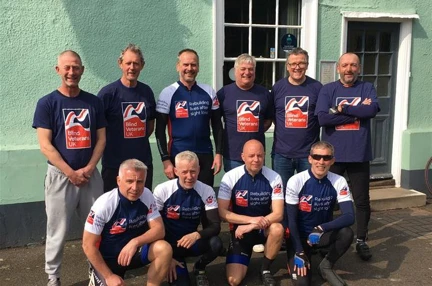 A group picture of ten men who make up the cyclists for the 400 mile bike ride and their support crew all wearing Blind Veterans UK tops