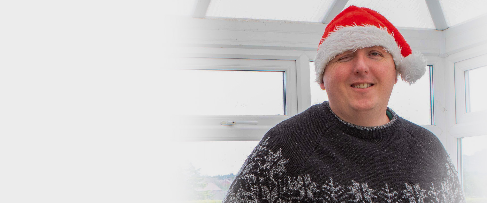 Photo of blind veteran Chris wearing a christmas hat smiling