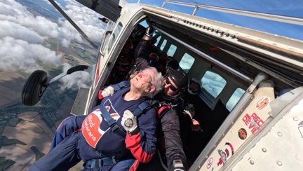 Danny strapped to the front of his instructor hanging out the edge of the plane at 13,000 feet
