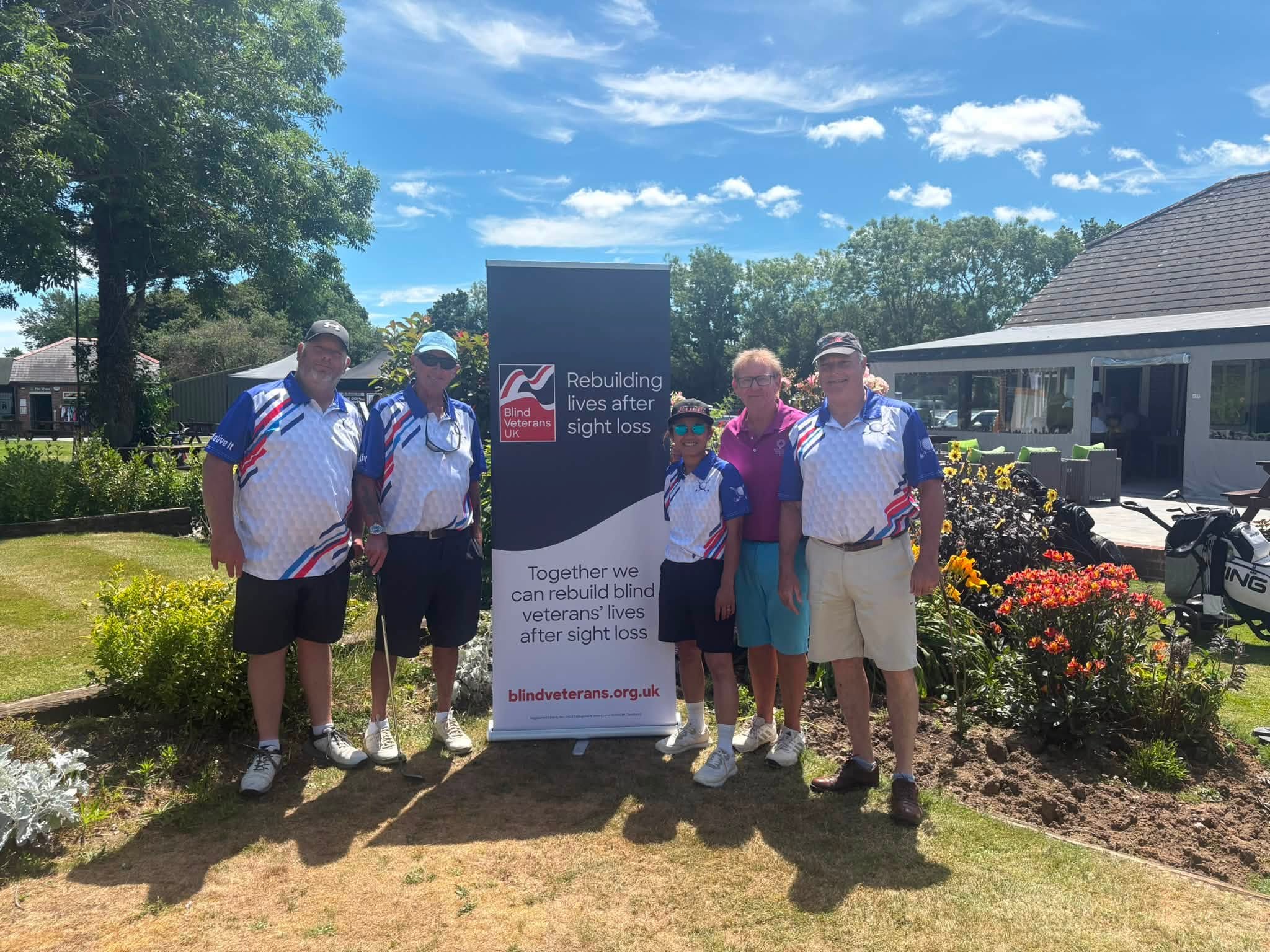 A group of golfers stood next to a Blind Veterans UK banner