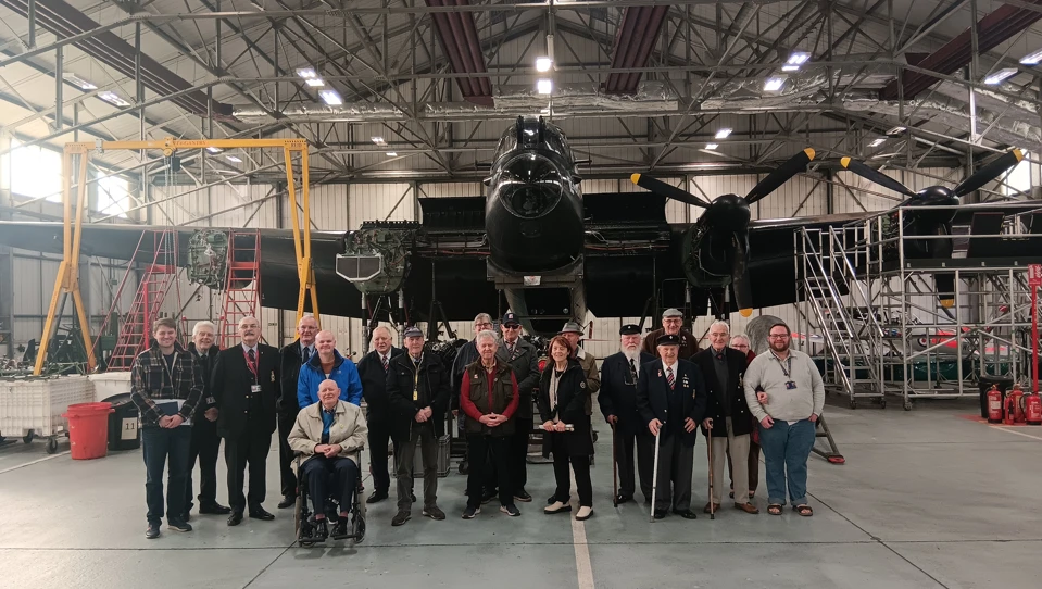 A group of Members, staff, and volunteers standing in front of a plane at RAF Conningsby