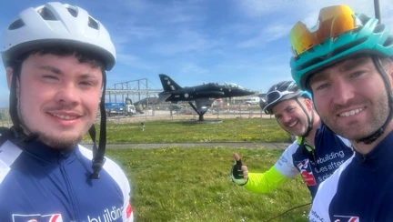 The three cyclists pose for a selfie in front of a hawk at RAF Valley
