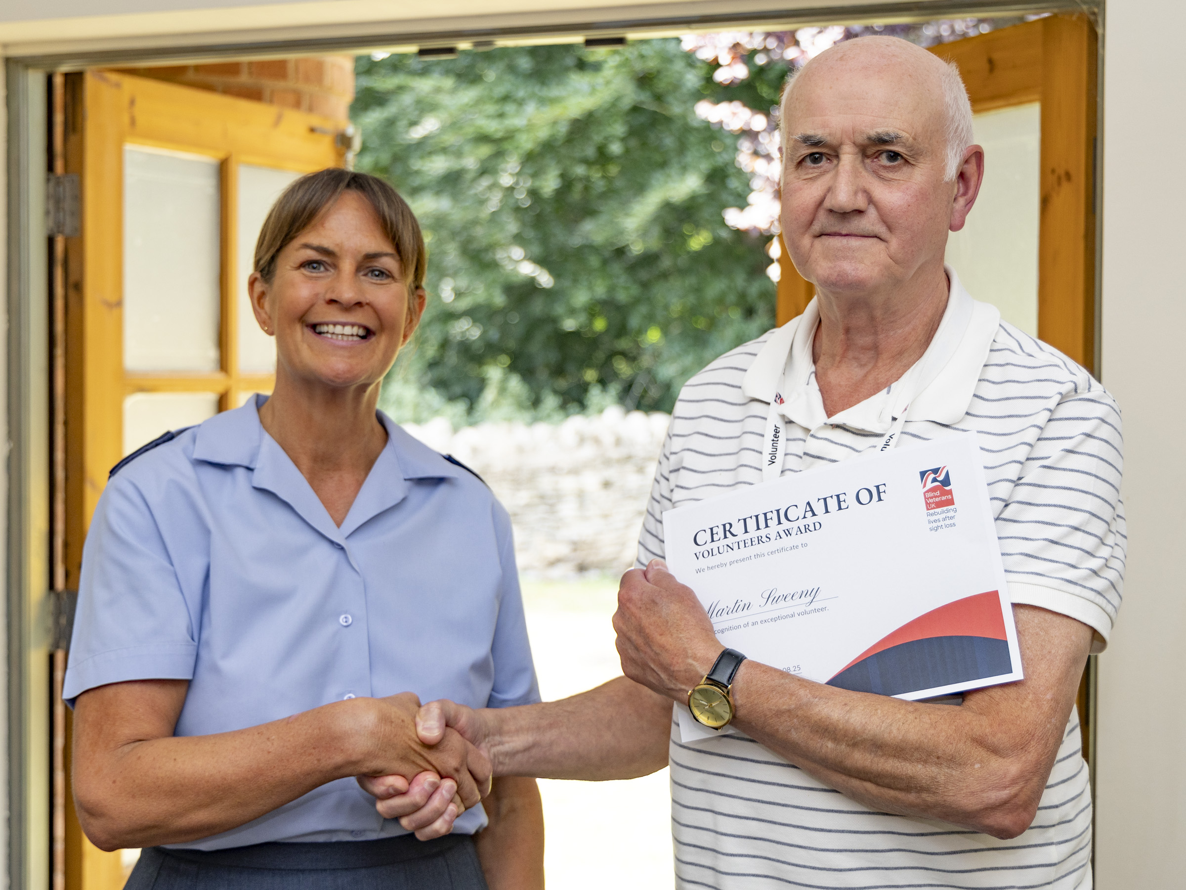 Volunteer Martin shaking hands with WO Tracey while holding his Founders Award certificate at RAF Cranwell.