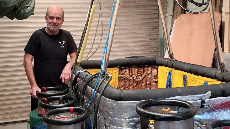 Blind veteran Mike stands next to the hot air balloon basket and gas canisters that will fuel his flight