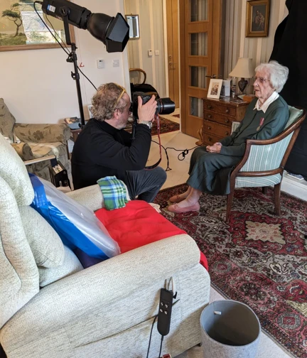 Ruth sits for a photograph in her living room as Richard Cannon holds a large professional camera.