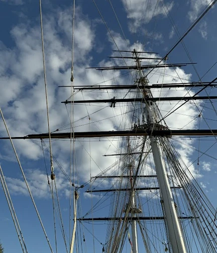 A photograph taken from the ground of Kelso up high on the mast, halfway along the yard arm