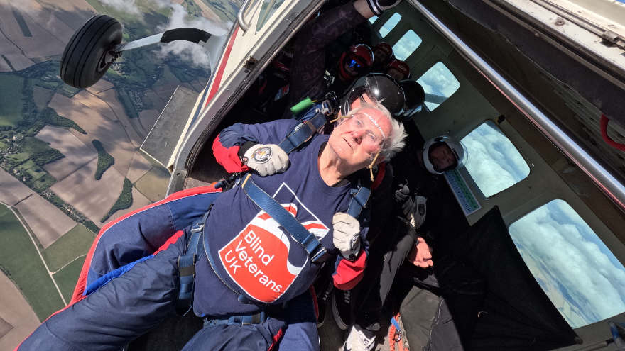 Blind veteran Danny wearing a Blind Veterans UK jumper as he hands out a plane at 13,000 feet, ready to take his jump