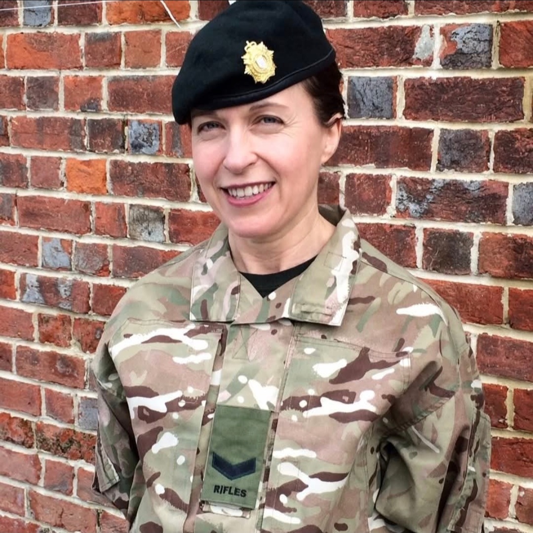 Vicky in her military uniform stood with a brick wall behind her