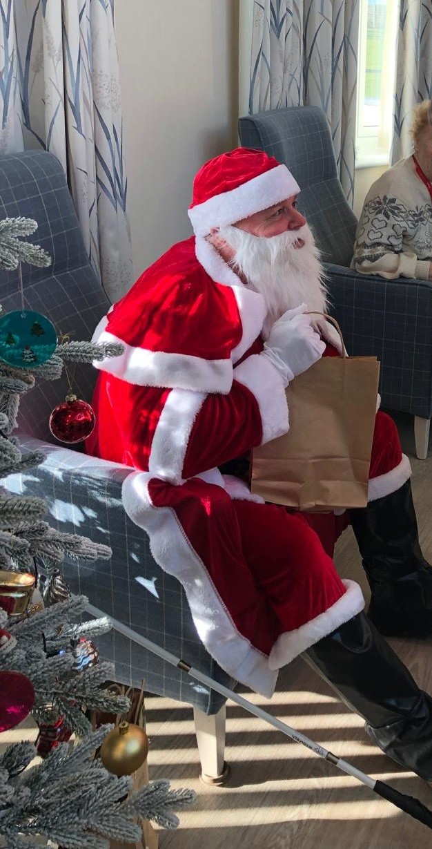 A blind veteran dressed as Father Christmas sat next to a Christmas tree