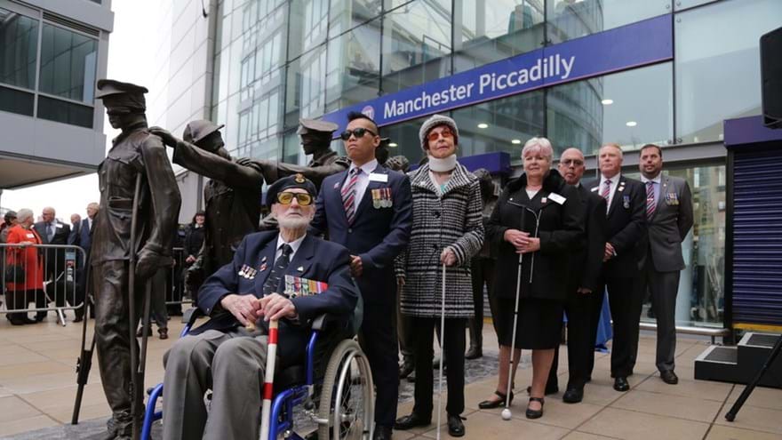 Photo of seven of the blind veterans we support stand next to our statue, Victory Over Blindness.