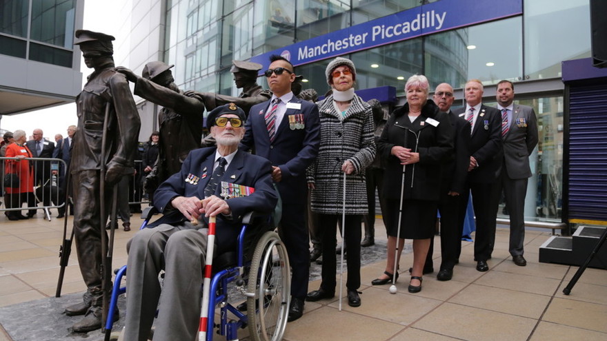 Seven blind veterans next to our Victory Over Blindness statue outside Manchester Piccadilly station