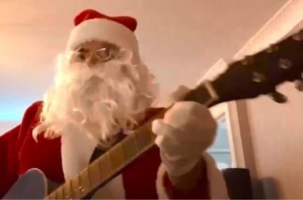 A man dressed as Santa Claus playing guitar