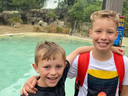 Two boys stood with their arms around each others shoulders and smiling