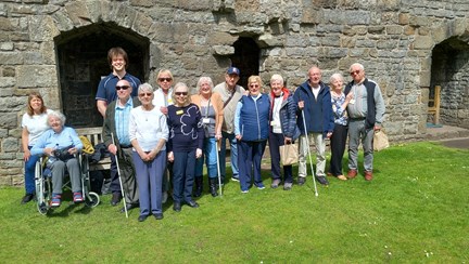 A group of blind veterans posing for a photograph in front of a castle wall