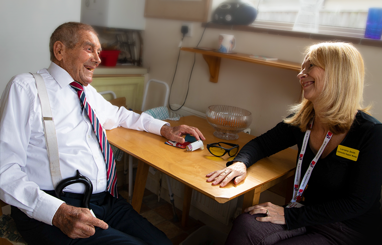 Blind veteran Eddie sitting at a table with Lorraine, looking at each other as they both smile