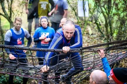 Mark, a blind veteran, doing an obstacle course with others cheering him on