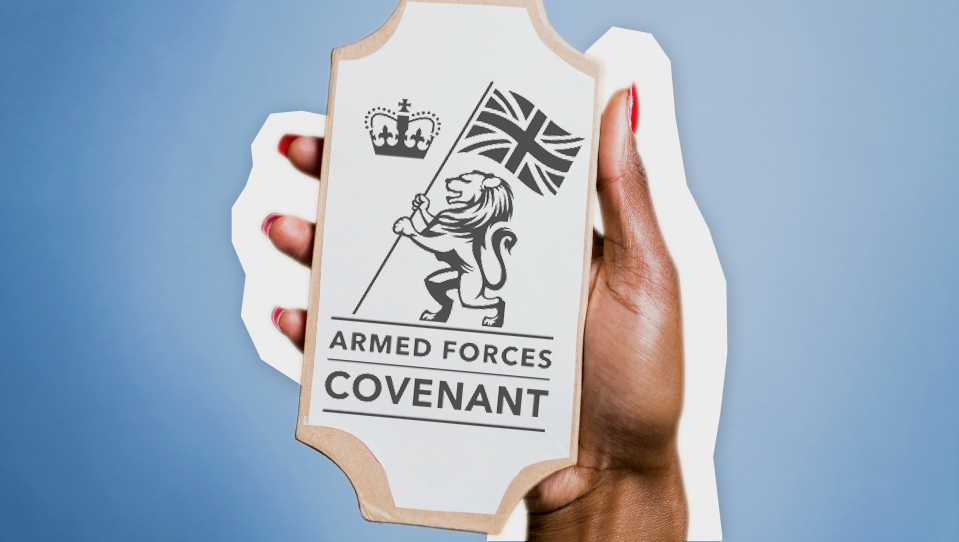 A hand holding up an Armed Forces Covenant logo