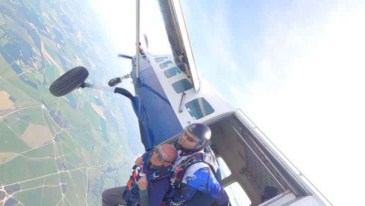 Mark with his tandem instructor strapped to the back of him as they exit the open plane door