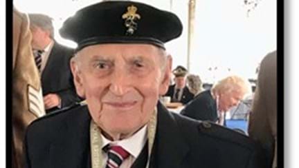 Blind veteran John at an event wearing his beret and military medals