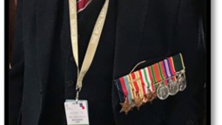 Blind veteran John at an event wearing his beret and military medals